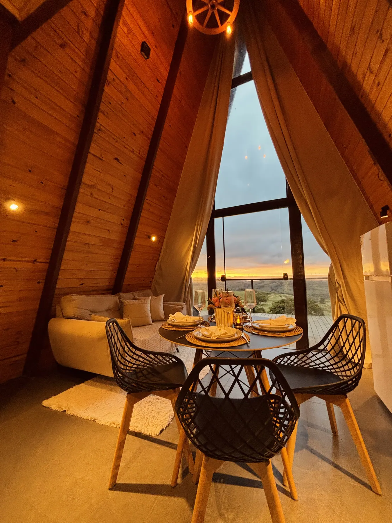 Interior do chalé com mesa posta e vista para a serra